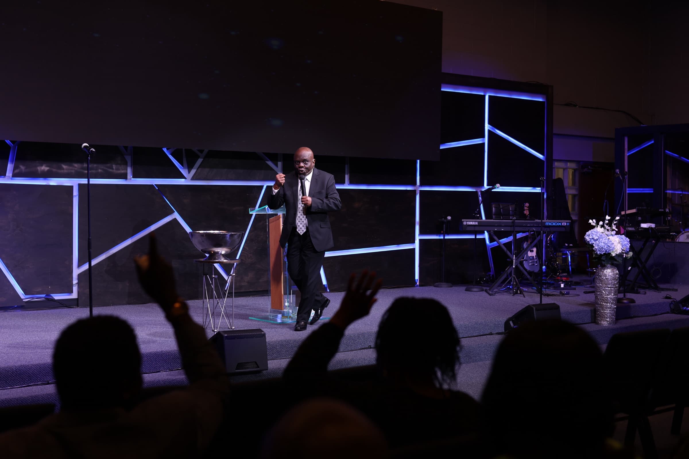 Pastor Nnaemeka Uchegbu preaching as the congregation raises their hands